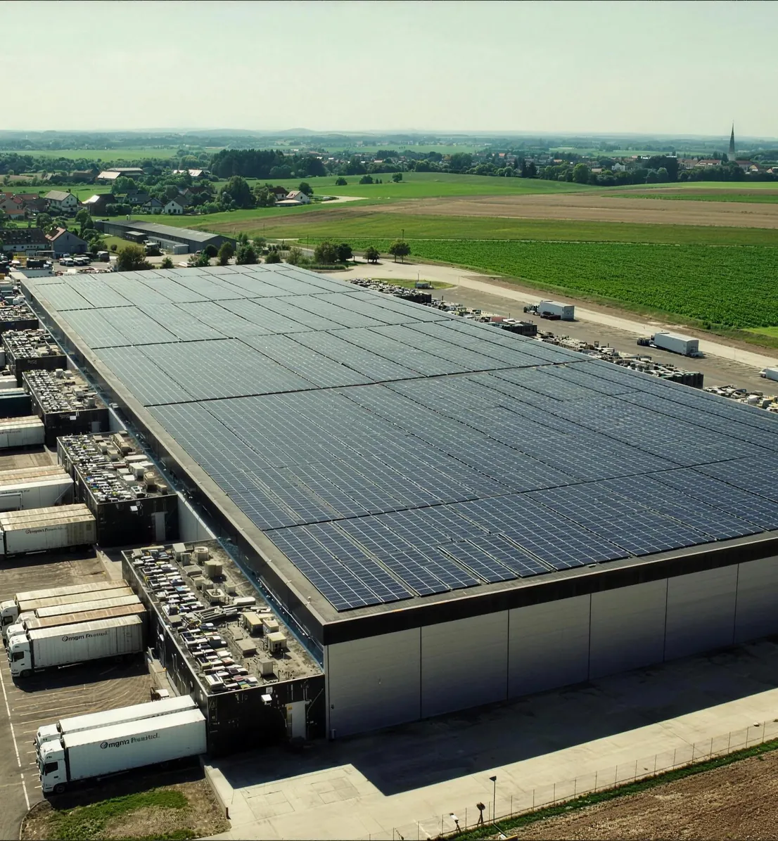 Luftaufnahme eines Logistikzentrums mit Solardach und Lkw an den Laderampen