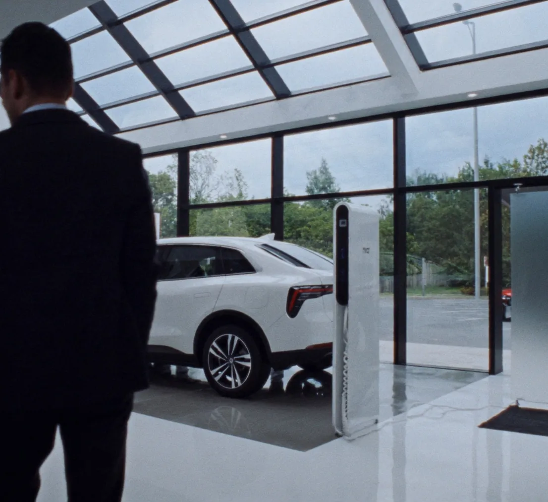 Autohaus-Showroom mit Elektroauto, DC-Ladesäule und Verkaufsberater